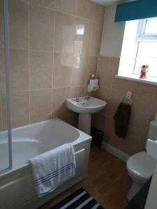 a bathroom with a white tub and a sink at Cheerful 3-bedroom townhouse with free parking on site in Taunton