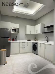 a kitchen with white cabinets and a washing machine at Kease Malqa D-12 Royal Touch GZ20 in Riyadh