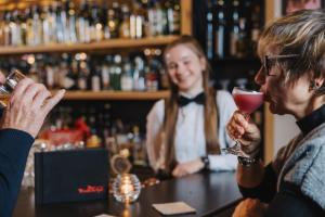a woman drinking a glass of wine at a bar at Der Rindererhof in Tux