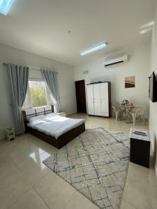 1 dormitorio con cama y alfombra grande en للإيجار استوديوهات ضمن فيلا جديده كلياً, en Al Khawḑ