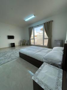 1 dormitorio con 2 camas y ventana grande en للإيجار استوديوهات ضمن فيلا جديده كلياً, en Al Khawḑ