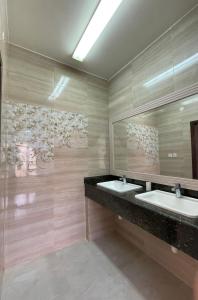 a bathroom with two sinks and a large mirror at للإيجار استوديوهات ضمن فيلا جديده كلياً in Al Khawḑ