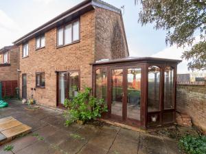 an enclosed greenhouse in front of a brick house at Spacious Home with Modern Amenities Near IKEA Pass the Keys in Reading