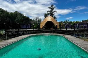 a swimming pool with a straw building in the background at ViewPoint Ecolodge in Nyaungshwe Township