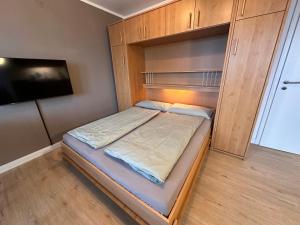 um pequeno quarto com uma cama e uma televisão em Watt & Wind - Tolles Schwimmbad em Cuxhaven