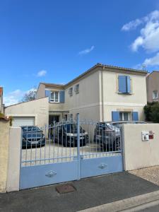 a gate in front of a house with parked cars at Les trois îles O.Ré.A. in Aytré