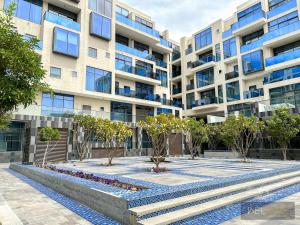 an apartment building with trees in the courtyard at WelHome - Prime 1BR Apartment at Oia Residence in Dubai