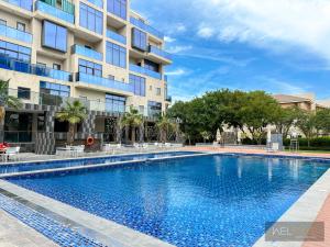 a swimming pool in front of a building at WelHome - Prime 1BR Apartment at Oia Residence in Dubai