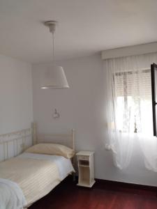 una camera bianca con un letto e una finestra di Agradable adosado familiar a La Laguna