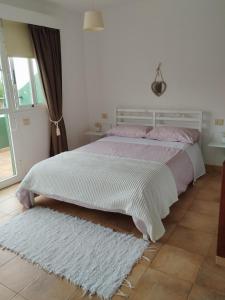 una camera con un letto bianco e un tappeto bianco di Agradable adosado familiar a La Laguna