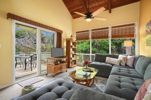 ein Wohnzimmer mit einem Sofa und einem TV in der Unterkunft Kauai Birdsong At Poipu Crater in Koloa