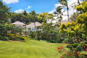 ein Haus mit Palmen und einem grünen Hof in der Unterkunft Kauai Birdsong At Poipu Crater in Koloa