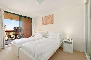 a white bedroom with a bed and a balcony at Spacious 3-Bed with Alfresco Dining by Amenities in Sydney