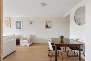a white living room with a table and chairs at Spacious 3-Bed with Alfresco Dining by Amenities in Sydney