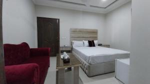 een slaapkamer met een bed en een rode stoel bij HOTEL MEDALLION EXPO in Lahore