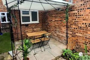 a patio with a bench and an umbrella at Cosy and Modern 2 Bedroom Home in Faulkner St., Chester in Chester