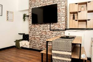 a living room with a stone wall with a flat screen tv at Cosy and Modern 2 Bedroom Home in Faulkner St., Chester in Chester