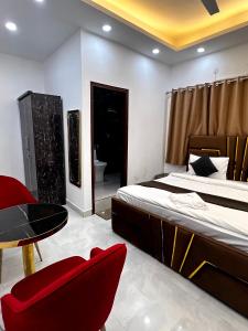 a bedroom with a bed and a red chair and a table at Hotel Trending Stay in New Delhi