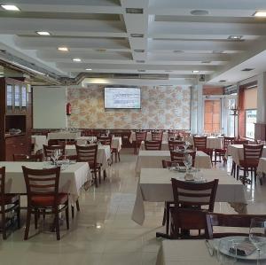 un restaurant avec des tables et des chaises blanches et un écran dans l'établissement Apartamento Río Gallo, à Cuntis