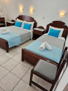 ein Zimmer mit 2 Betten und einem Stuhl darin in der Unterkunft Hotel Leta in Fira