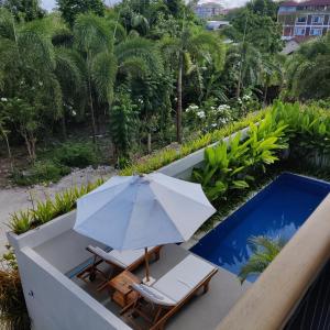 an umbrella and chairs on a balcony with a pool at SUNNYRENT. Guest villa Dreamland in Ungasan