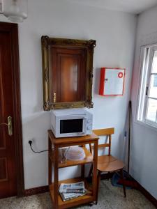 a microwave on a table with a cabinet on the wall at Pensión Glorioso Hostel in Picaraña