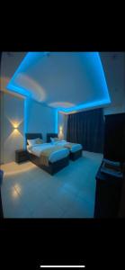 a bedroom with a bed with a blue lighting at الديوان النجدي للشقق المخدومة in Ukaz