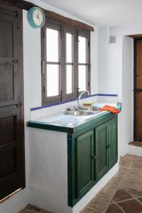 een keuken met een wastafel en een klok aan de muur bij Casa Rural Los Sentidos Jimena in Jimena de la Frontera