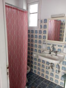 a bathroom with a pink shower curtain and a sink at Valasis Studios in Argasi