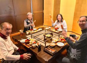 un grupo de personas sentadas alrededor de una mesa comiendo comida en The Ninja Mansion, en Toyota