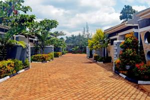 a brick road in a courtyard with flowers and plants at Serene Homes in Jinja