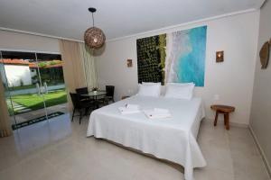 a bedroom with a large white bed and a table at Parada IT in Japaratinga