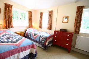a bedroom with two beds and a dresser and windows at Penwaun Nevern in Nevern