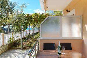 a table with wine glasses on a balcony with a window at Lampiris Beach Front Apartments in Potos