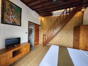 un salon avec une télévision et un escalier dans l'établissement Relaxing 2 Bedroom Villa With Private Pool, à Ubud