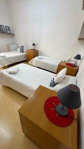 een kamer met drie bedden en een tafel met een lamp bij Malta Crown guesthouse in St Julian's