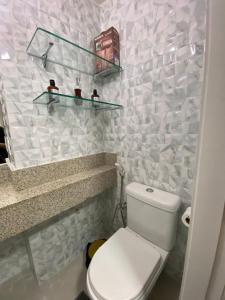 a bathroom with a white toilet and some shelves at Escala Landscape Beira Mar in Fortaleza