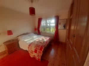 a bedroom with a bed and a window with red curtains at Close to Lough Rynn Castle Mohill - Room Only in Mohill