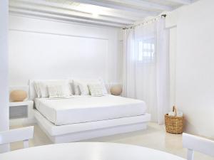 a white bedroom with a white bed and a window at Mykonos Lolita, A Grecotel Resort to Live in Agios Sostis Mykonos