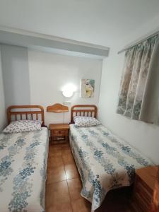 a bedroom with two beds and a table and window at Parque Royal Apartamento in Playa Fañabe