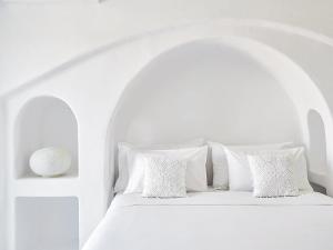 a white bedroom with a white bed with white pillows at Mykonos Lolita, A Grecotel Resort to Live in Agios Sostis Mykonos
