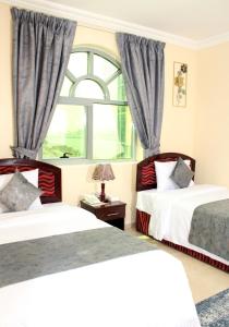 a bedroom with two beds and a window at Al BARAKAH HOTEL in Sharjah