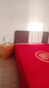 a bed with a red bedspread and a nightstand with a lamp at Apartments Happy Day in Karlobag