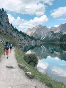 2 personnes marchant sur un chemin à côté d'un lac dans l'établissement Hotel Das Urbisgut, à Altenmarkt im Pongau