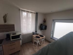 a bedroom with a desk and a table and a window at Studio proche centre in Pontarlier