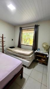 Habitación pequeña con 2 camas y ventana en Casa de temporada na Serra Macaense, en Macaé