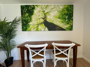 een tafel met twee stoelen en een schilderij aan de muur bij Cozy Self Contained Studio with Seperate Spacious Living room -Just a Stone's Throw from Newly Renovated Knox Westfield in East Melbourne in Wantirna South