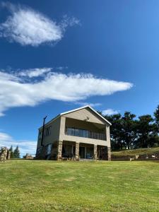a large building on a grass field with a blue sky at Zamenkomst River Lodge in Maclear