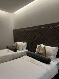 duas camas num quarto de hotel com uma grande cabeceira em شاليه فيلا غرفتين نوم em ‘Anqāʼ