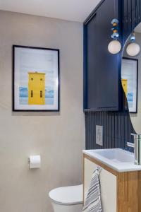 a bathroom with a toilet and a picture of a yellow building at Designer Gem in the Old North by FeelHome in Tel Aviv